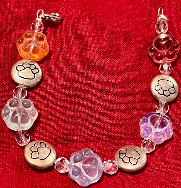 Photo of bracelet with paw print beads in silver clear orange and lavender.